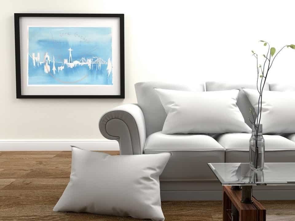 A living room with a white couch adorned with a captivating blue Lisbon Print, adding a touch of Portugal Shop flair to the wall decor.