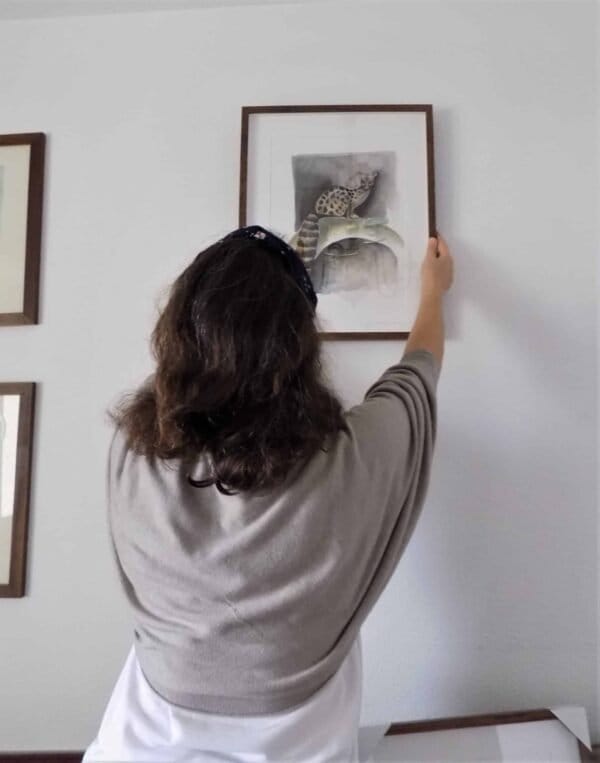 A woman is putting a Common Genet Print on a wall from the Portugal Shop.