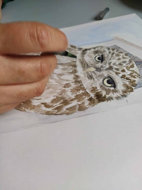 A person is painting a Little owl print on a piece of paper.