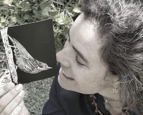 A woman holding up a black and white fine art print of a butterfly.